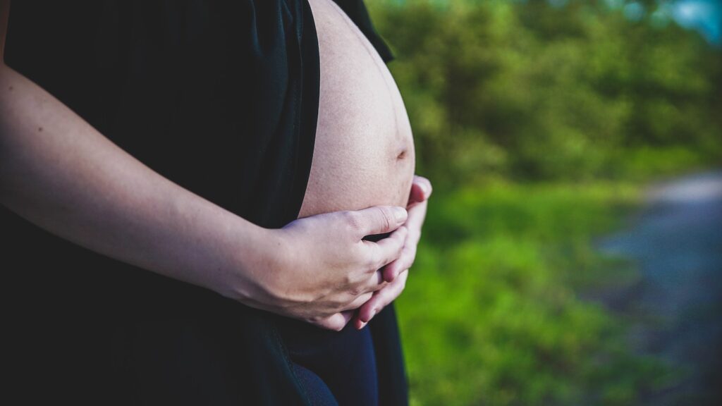 a pregnant woman is holding her stomach outside