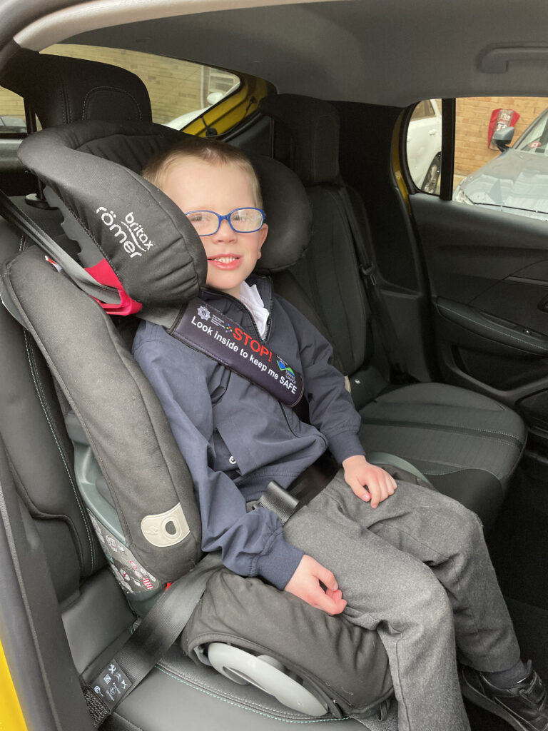 Child wearing one of the new Project Treasure seatbelt covers