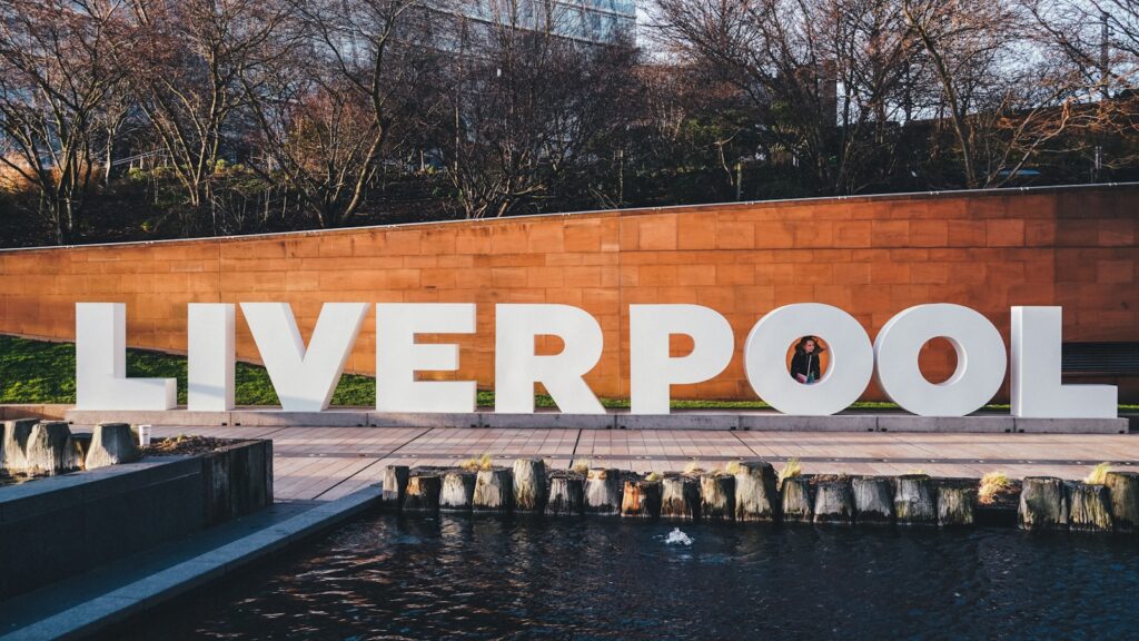 a large sign that says liverpool next to a body of water