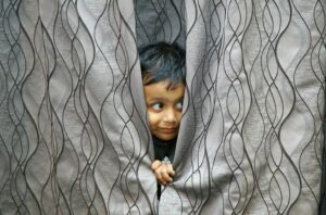 boy hiding behind of gray textile