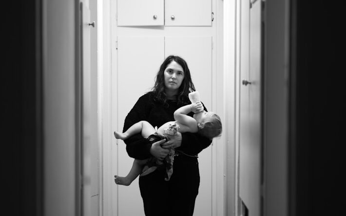 woman in black long sleeve shirt carrying baby in grayscale photography