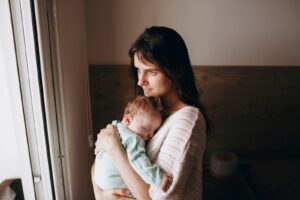 A serene image of a mother lovingly holding her sleeping baby indoors.