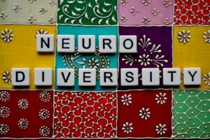 The word neurodiversity spelled out in white letter tiles on a colorful patterned background